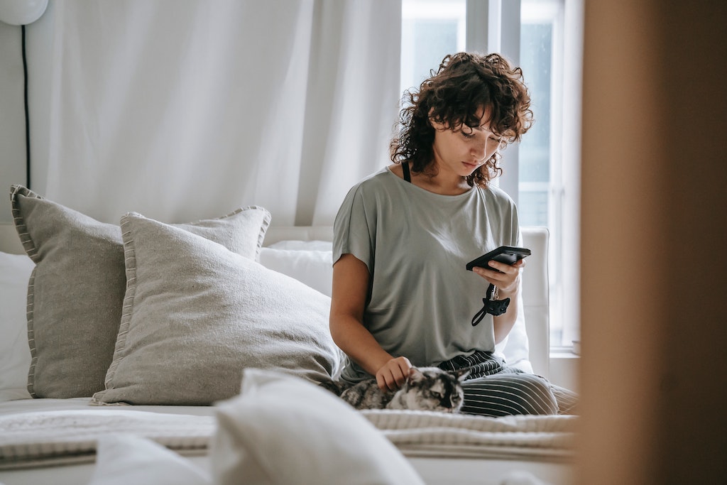 woman with phone on bed using the app